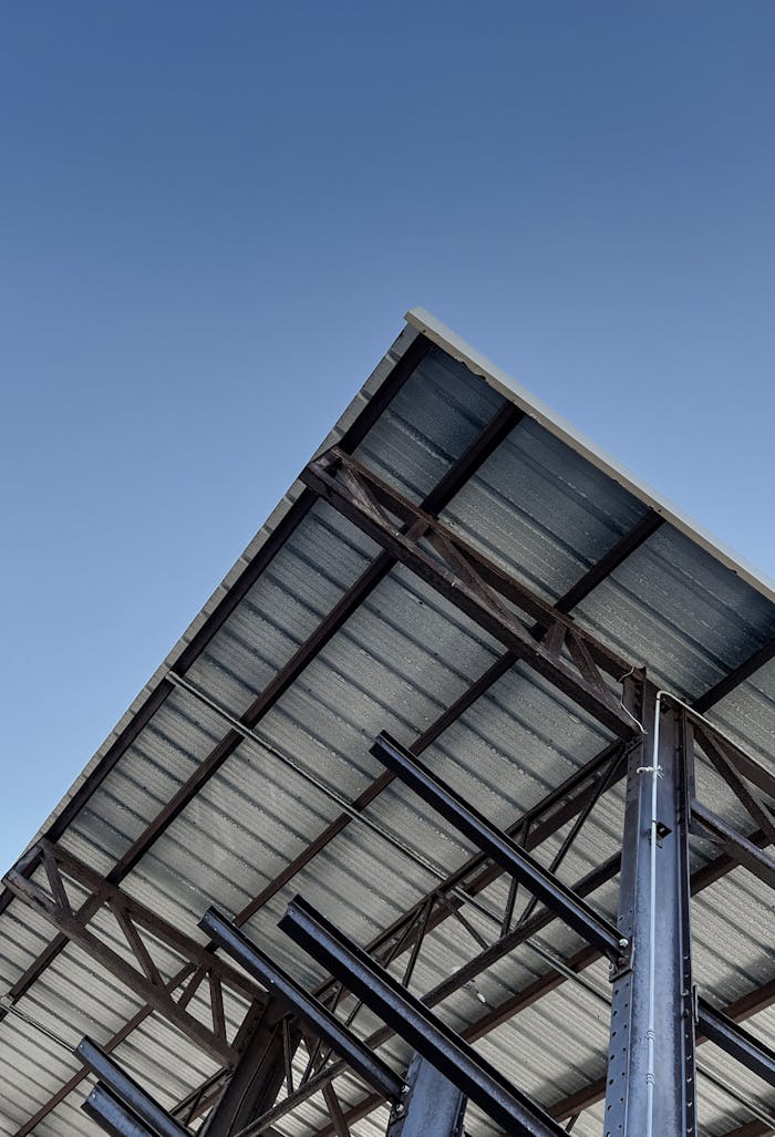 Angled view of an under-construction steel frame building with a clear blue sky backdrop.